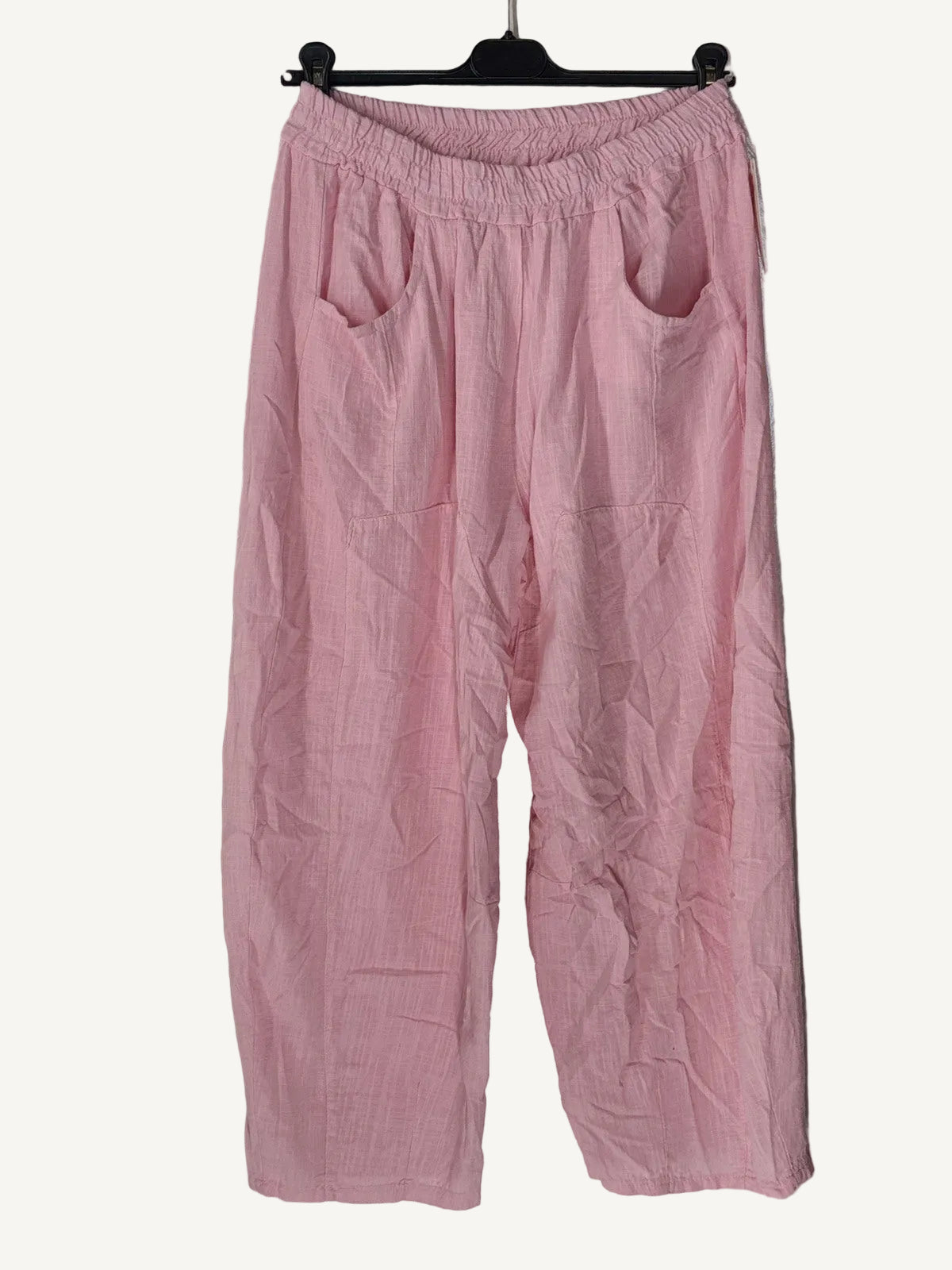 Pink pants on a hanger against a textured white wall