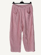 Pink pants on a hanger against a textured white wall