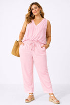 Woman wearing a pink top & trouser with a white background