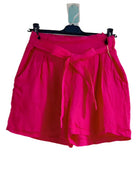 Pink shorts on a hanger against a white background