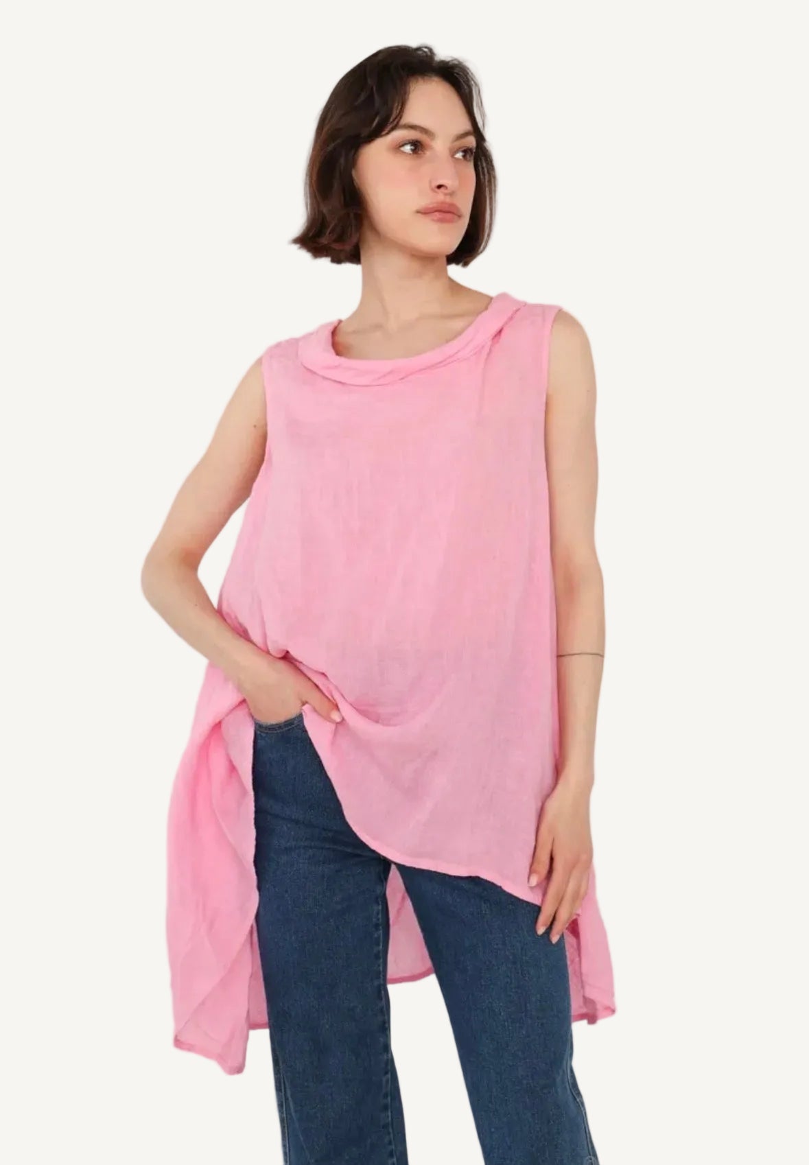 Woman wearing a pink sleeveless top and blue jeans on a white background