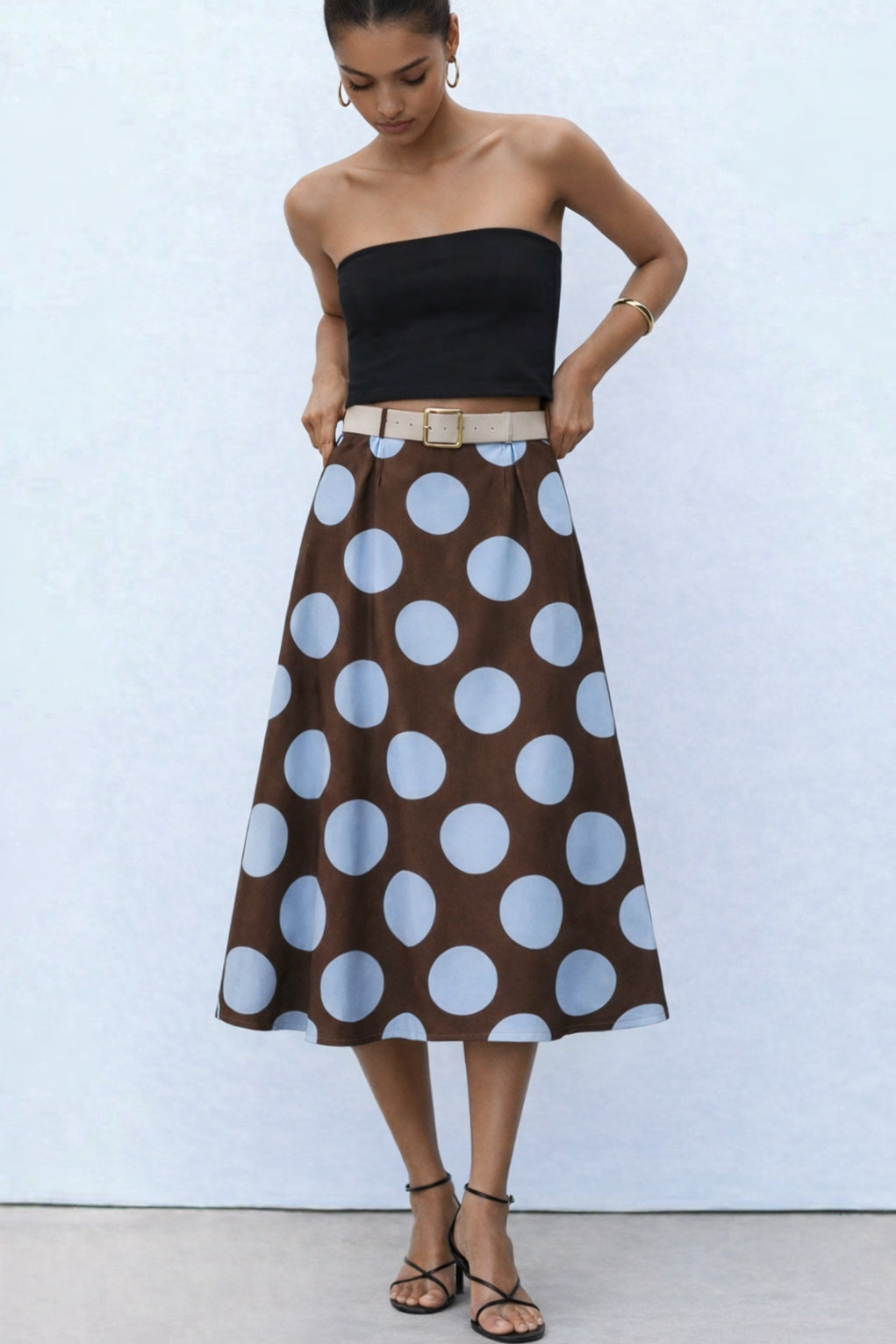 Woman wearing a black strapless top and brown polka dot skirt 
