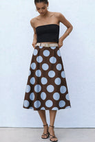 Woman wearing a black strapless top and brown polka dot skirt 