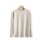 A light beige crewneck sweater hanging on a wooden hanger 