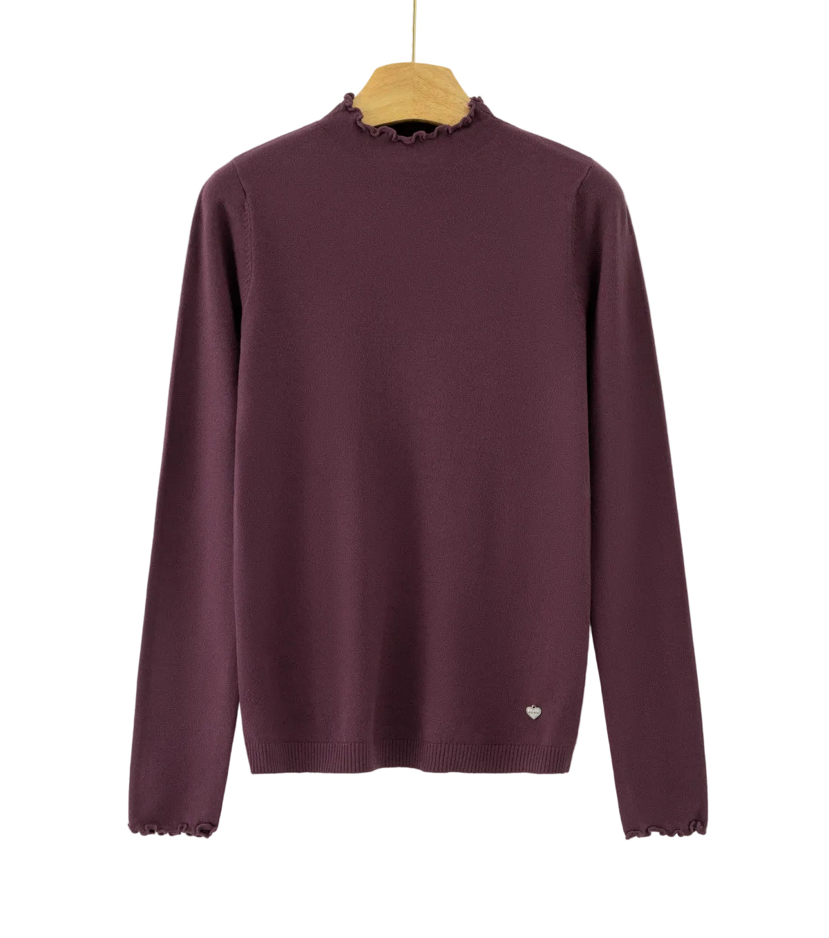 A long-sleeve knit sweater in deep plum purple, hanging on a wooden hanger against a plain white background. The sweater features a mock neck with delicate ruffled trim, matching ruffled trim along the cuffs, and a small white embroidered heart on the lower left hem.