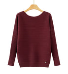 A ribbed knit long-sleeve sweater in deep burgundy, hanging on a wooden hanger 