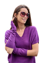 Woman wearing a purple sweater and sunglasses on a white background