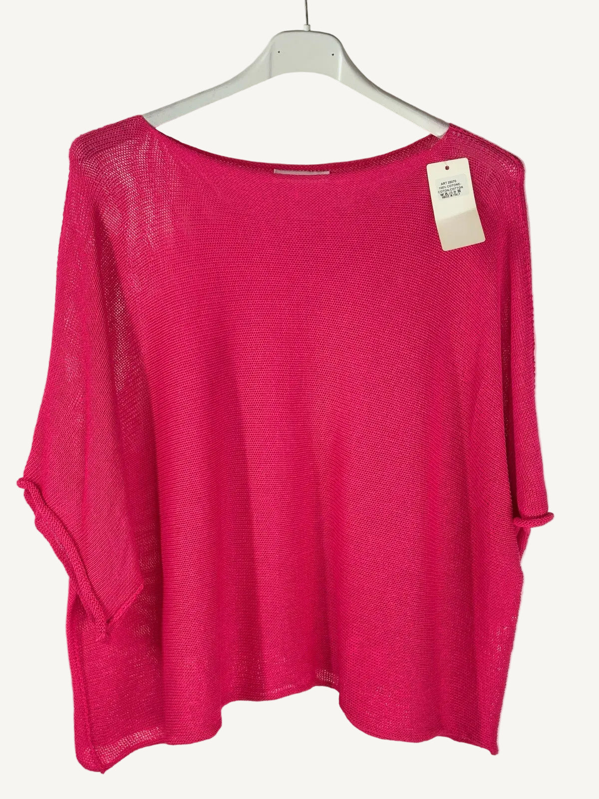 Pink sweater on a hanger with a visible tag against a neutral background