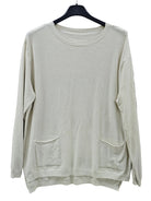 A cream-colored long-sleeve knit sweater with two front patch pockets, hanging on a black hanger