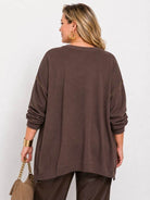 A woman shown from the back wearing an oversized brown long-sleeve top with decorative gold chain details along the upper sleeves, paired with brown pants, against a plain light background.