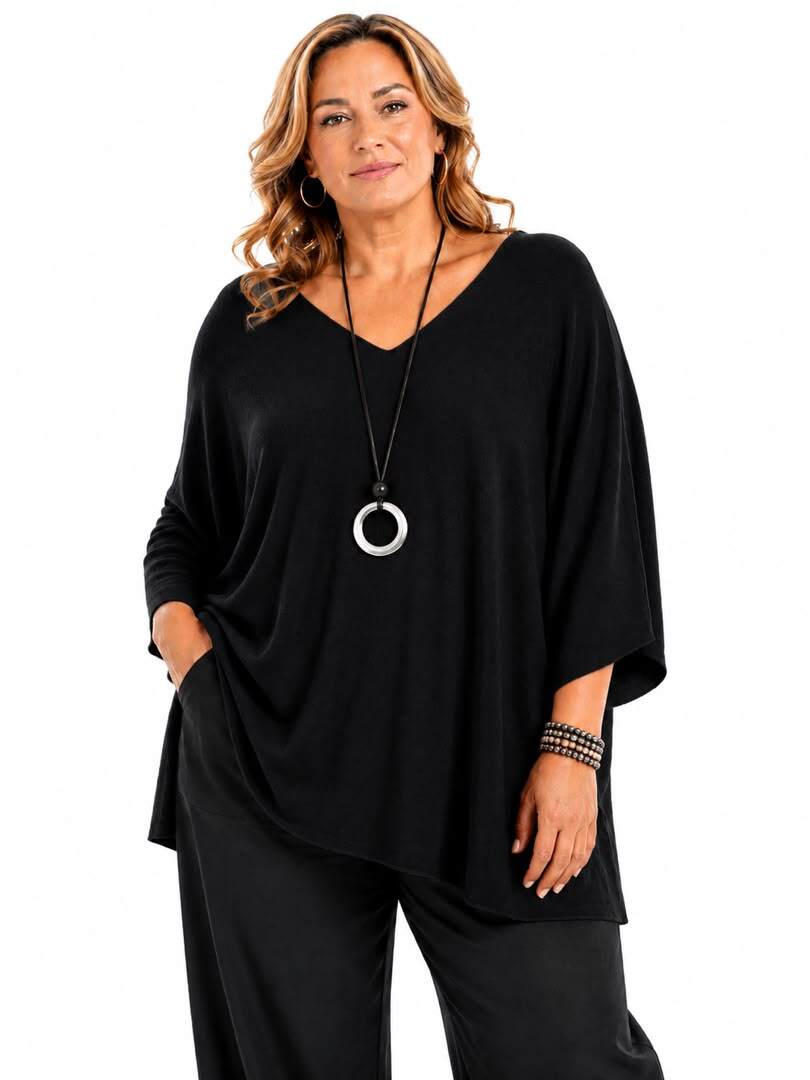 A woman modeling a black V-neck long-sleeve top with wide three-quarter sleeves and a relaxed silhouette, paired with black pants, against a plain white background.