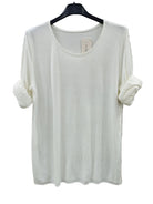 An off-white long-sleeve knit top with rolled-up sleeves, hanging on a black hanger 