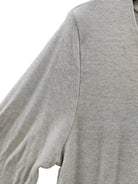 Close-up of a light heather gray knit top showing the shoulder seam and fine ribbed fabric texture.