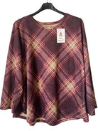 A women's long-sleeve top with a diagonal plaid pattern in burgundy, pink, and beige