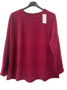 A deep burgundy long-sleeve crewneck top hanging 