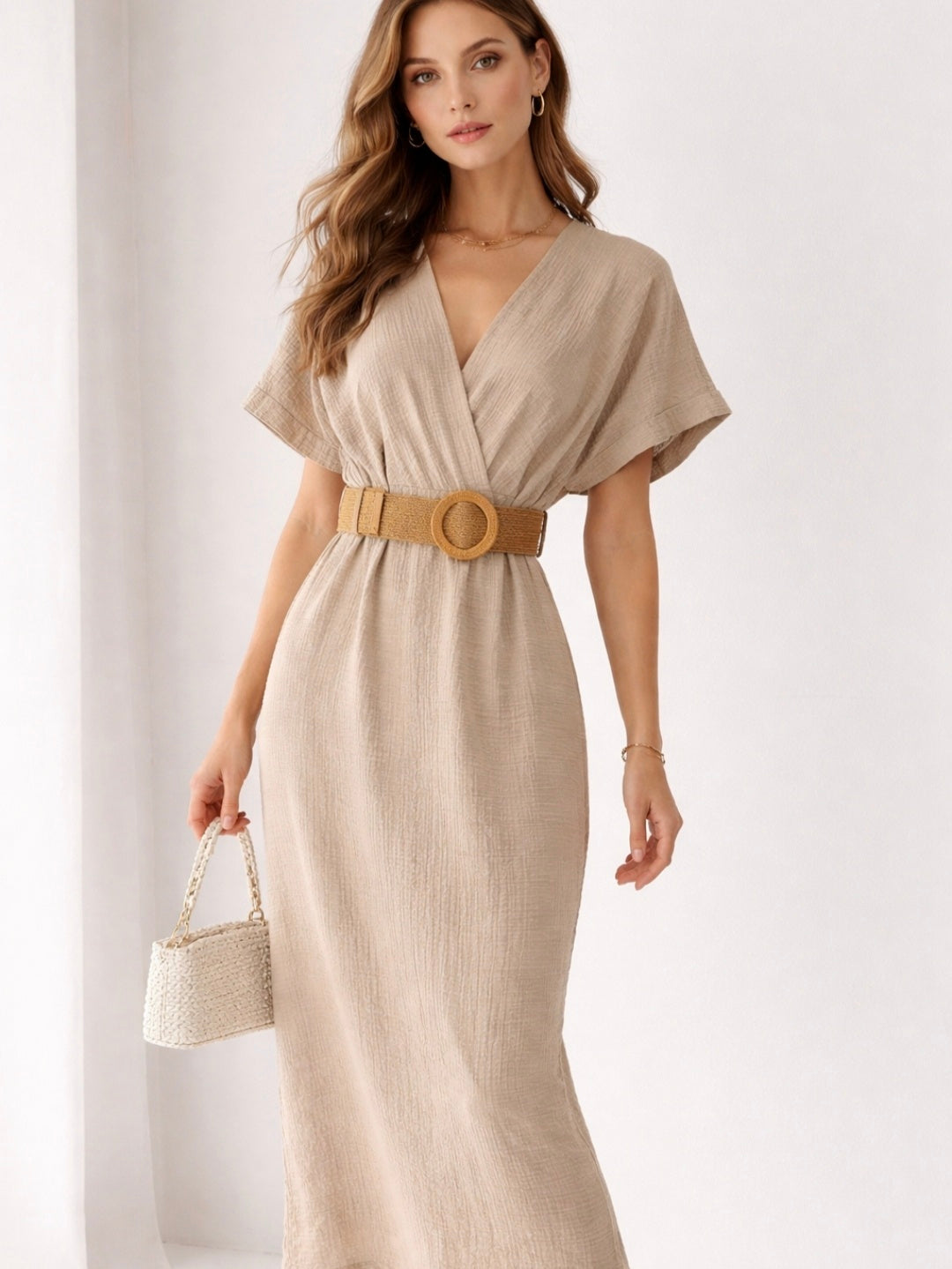 Woman wearing a beige dress with a belt on a white background