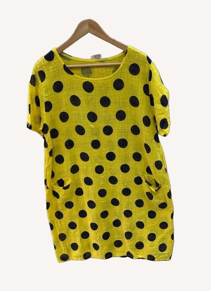 Yellow t-shirt with black polka dots on a hanger against a white background