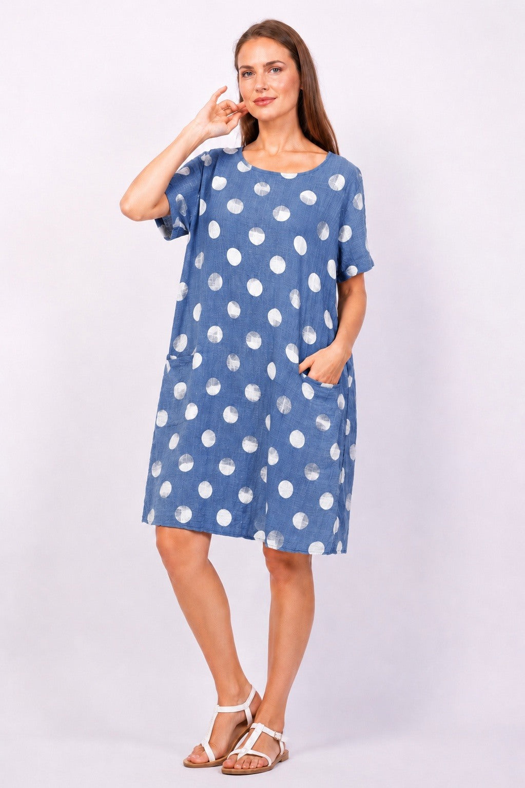 Woman wearing a blue dress with white polka dots on a white background