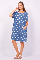 Woman wearing a blue dress with white polka dots on a white background