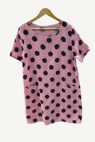 Pink dress with black polka dots on a hanger against a white background