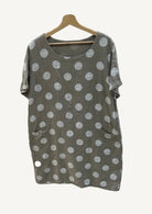 Taupe dress with polka dots on a hanger against a gray background