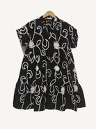 Black dress with white floral patterns on a hanger against a white background