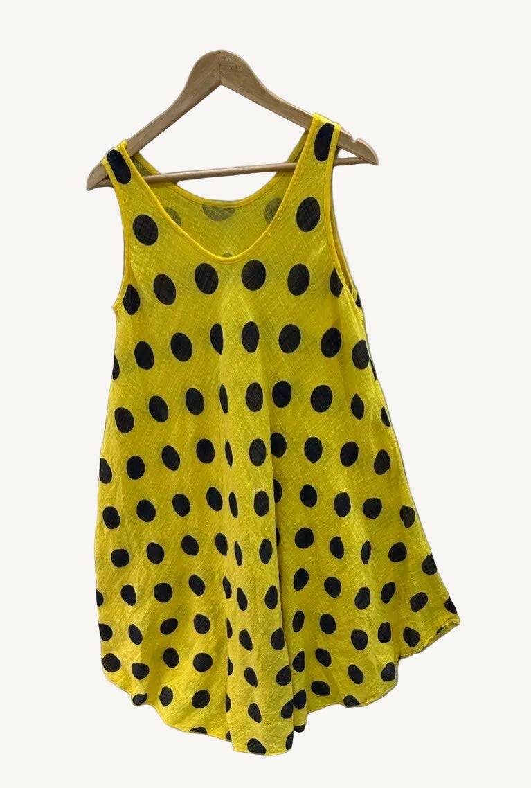 Yellow sleeveless dress with black polka dots on a hanger against a white background