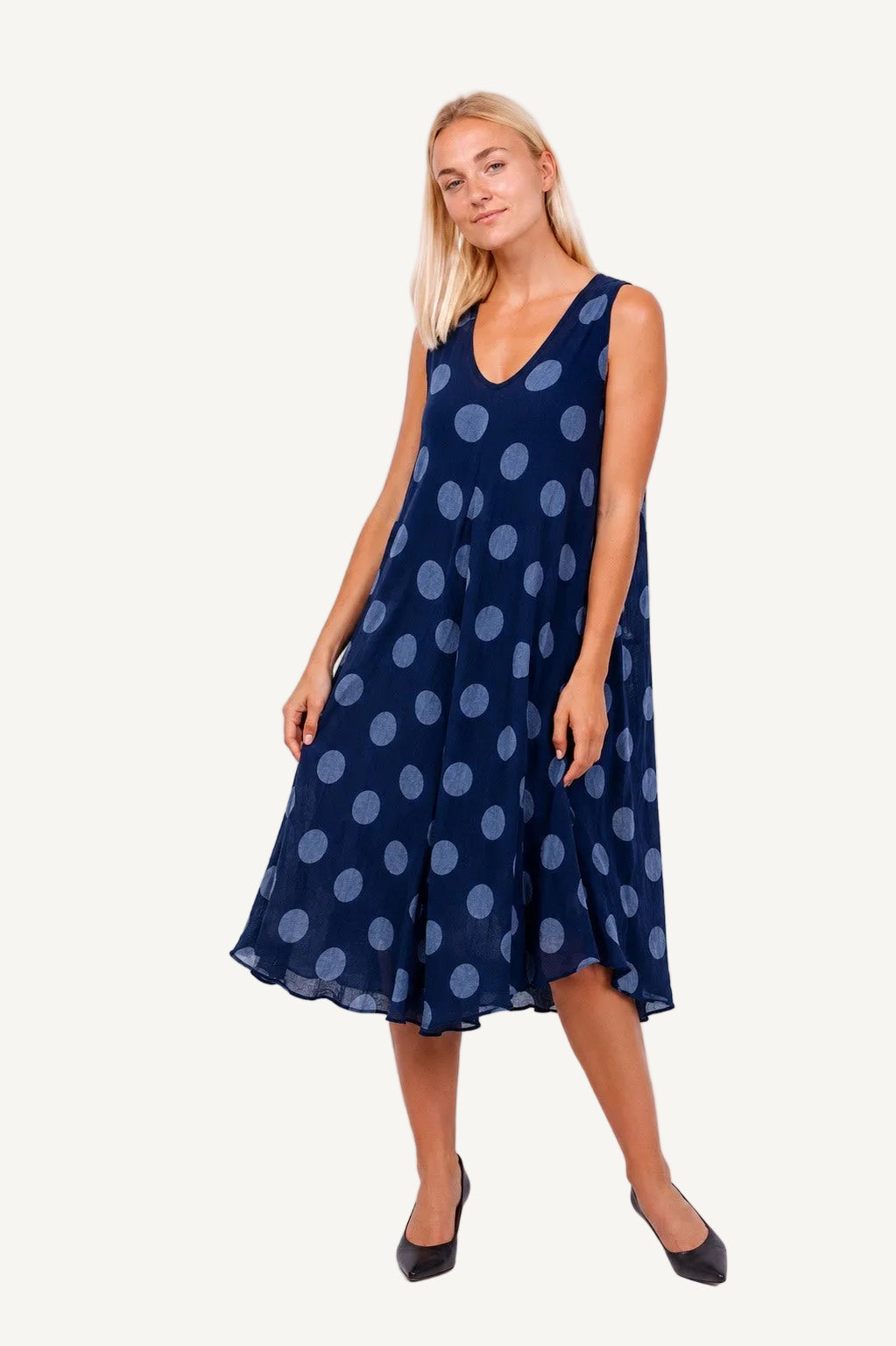 Woman wearing a navy dress with light blue polka dots on a white background
