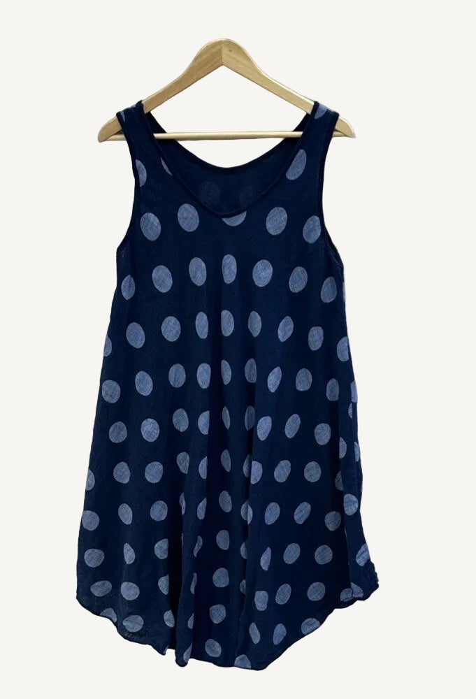 Navy blue sleeveless dress with white polka dots on a hanger against a white background