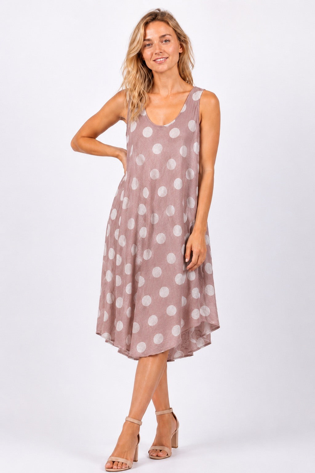 Woman wearing a sleeveless dress with white polka dots on a white background