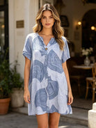 Woman wearing a blue patterned dress standing outdoors.