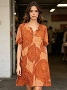 Woman wearing an orange patterned dress in a casual setting
