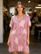 Woman wearing a pink patterned dress in an indoor setting