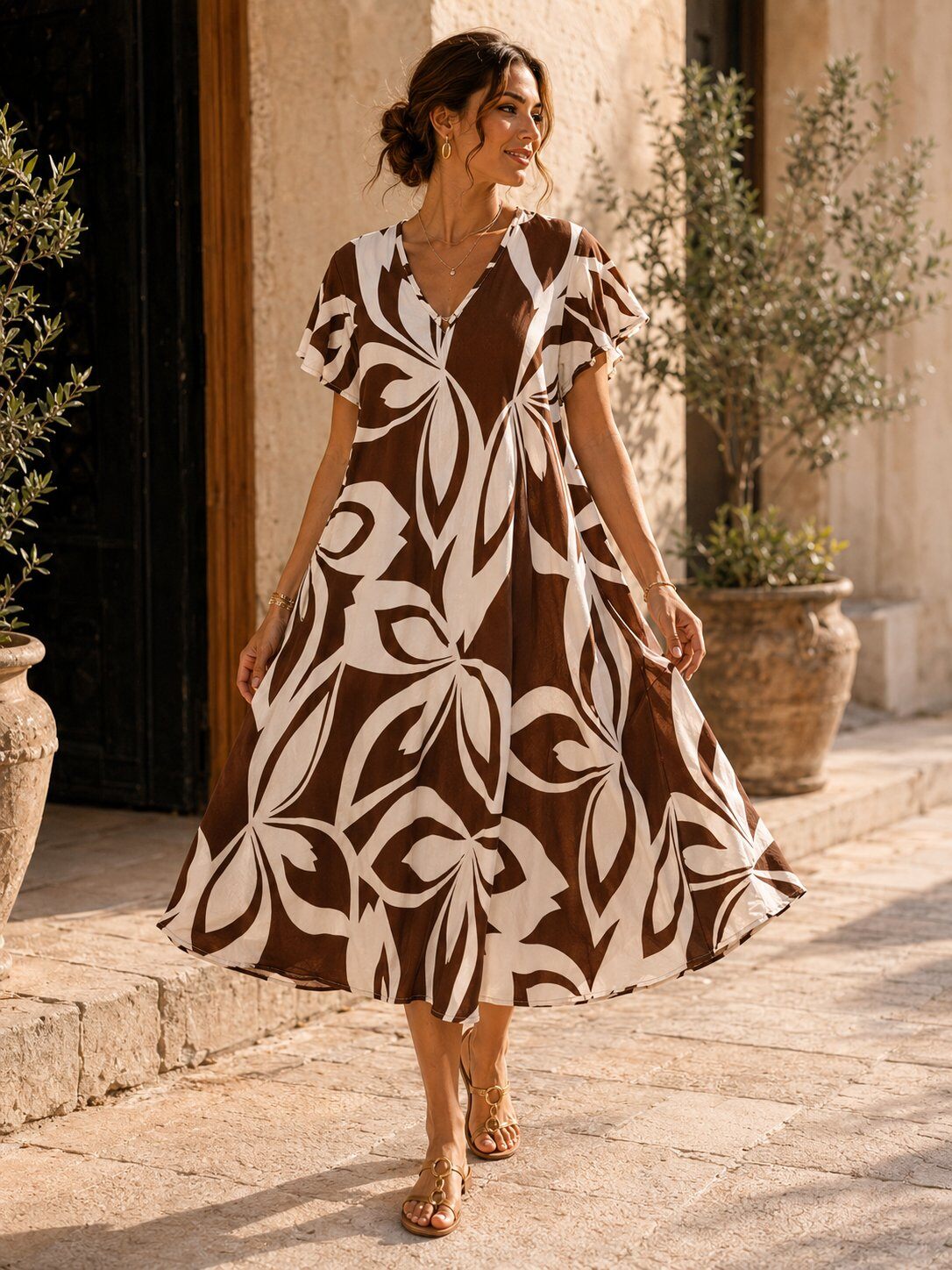 Woman wearing a brown and white patterned dress standing outdoors.