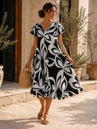 Woman wearing a black and white patterned dress standing outdoors.