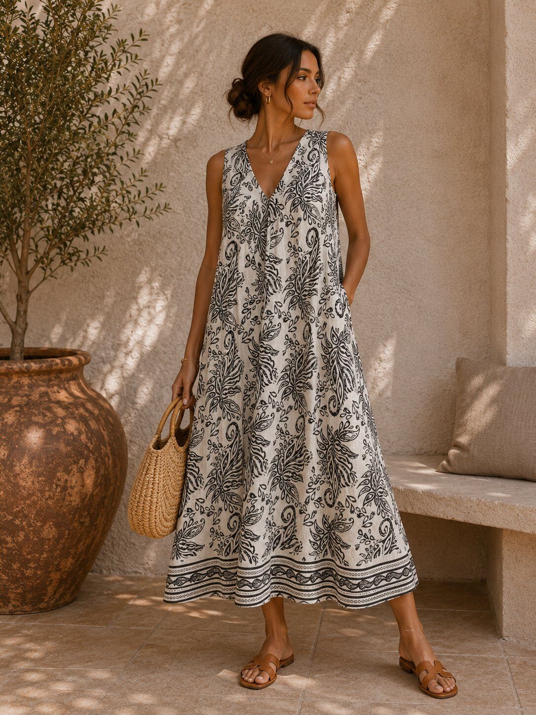 Woman wearing a black and white patterned dress standing in a sunlit outdoor setting.