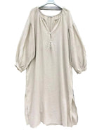 A light beige textured dress with three-quarter puff sleeves and a split neckline with a tassel detail