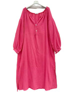 A bright pink textured cotton dress with a split neckline, three-quarter balloon sleeves,