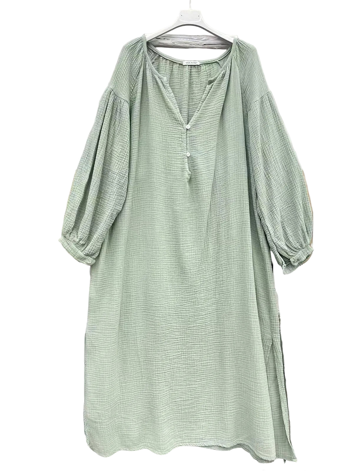 A light sage green textured dress with balloon sleeves and a split neckline, hanging on a white hanger