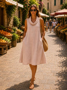 Woman in a light pink dress walking through an outdoor market.