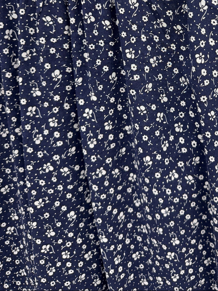 A sleeveless navy blue dress with a dense white daisy floral print