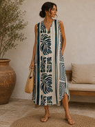 Woman wearing a long, patterned dress standing in a room with a plant and a couch.