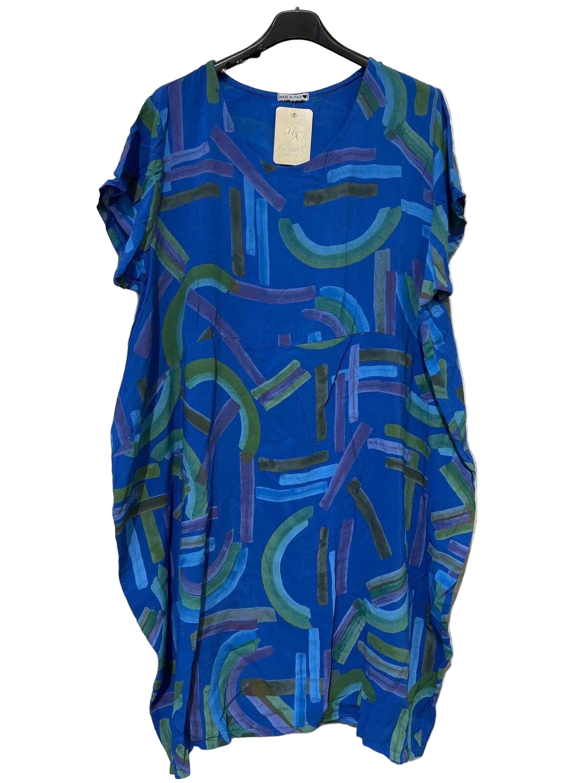 A loose-fitting short-sleeve dress with an abstract brushstroke pattern in shades of blue, green, and purple, hanging on a black hanger against a textured gray wall.