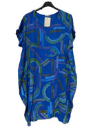 A loose-fitting short-sleeve dress with an abstract brushstroke pattern in shades of blue, green, and purple, hanging on a black hanger against a textured gray wall.