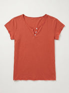 A short-sleeve henley t-shirt in a muted terracotta or burnt orange color, featuring a three-button placket, laid flat against a light gray background.