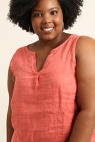 Woman wearing a coral sleeveless top against a beige background