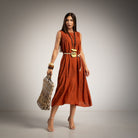 A woman models a sleeveless orange midi dress with a belt 