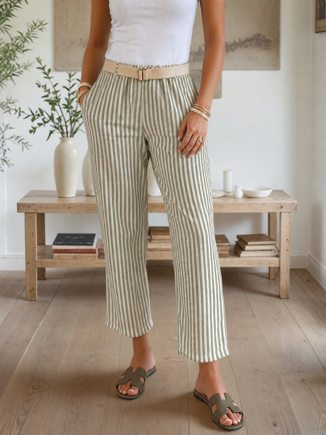 Person wearing striped pants in a room with wooden furniture and plants.