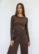 A woman modeling a matching brown long-sleeve top and wide-leg pants set 