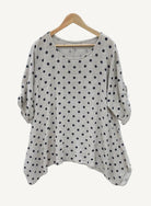 Beige sweater with black polka dots on a wooden hanger 